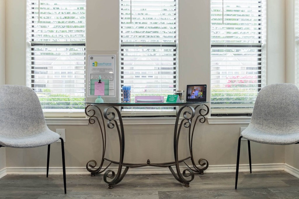 a desk with two chairs in front of two windows