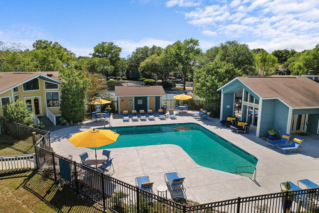 a swimming pool with chairs and umbrellas next to a house