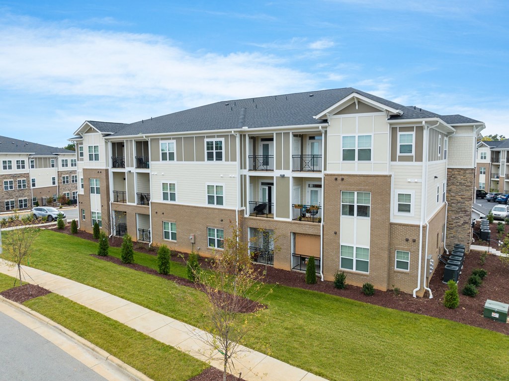an exterior view of an apartment building with a lawn