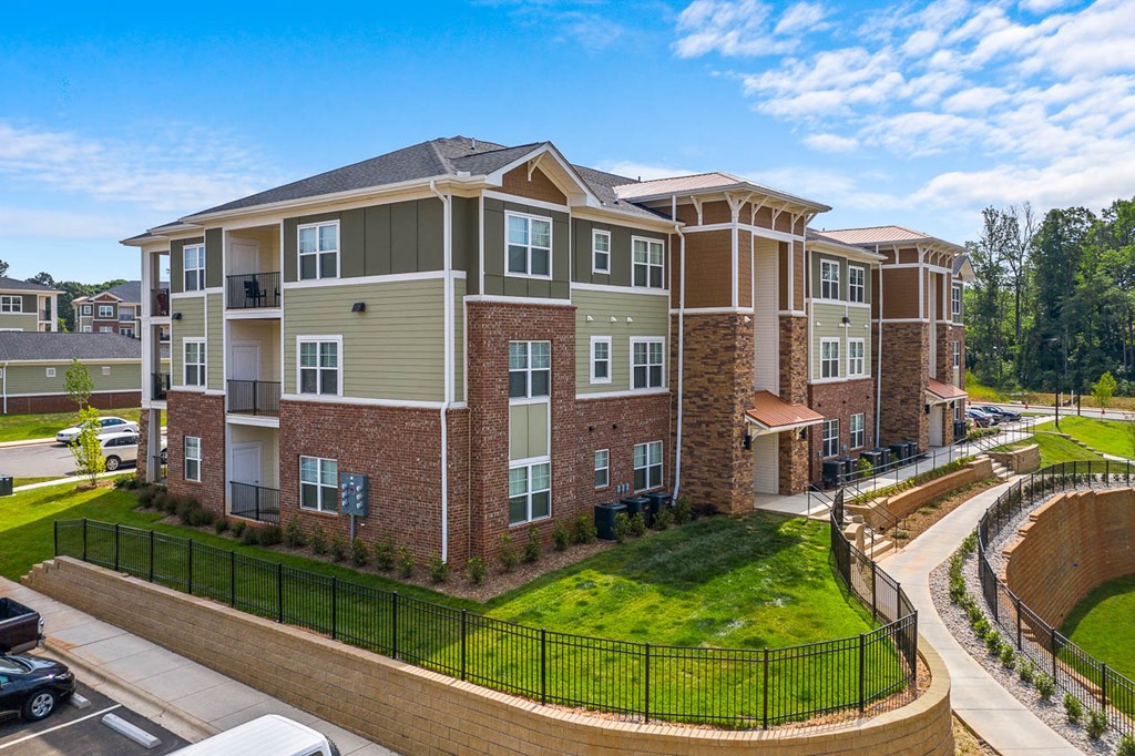 an aerial view of an apartment building with a green lawn and fence