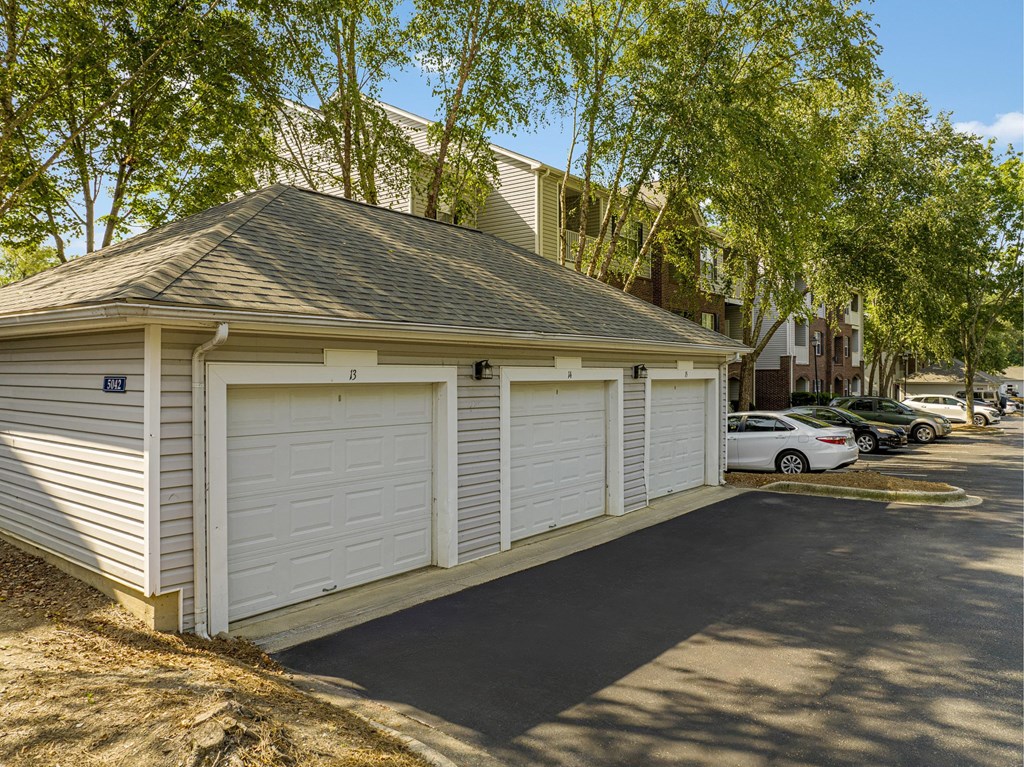 a small garage with white doors on the side of a street