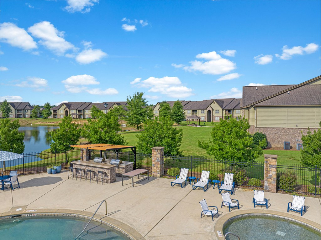 an aerial view of a pool and patio with chairs and a fire pit