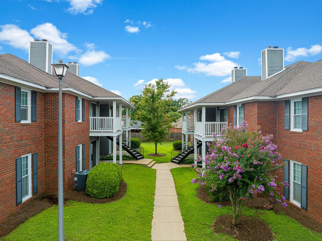 an image of an apartment complex with a walkway and grass