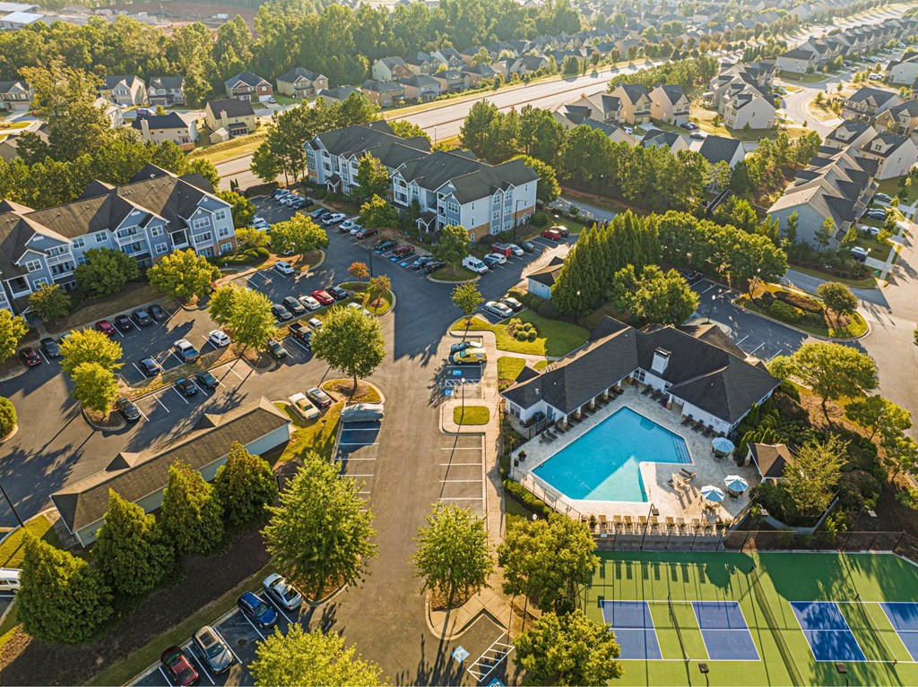 an aerial view of a neighborhood with a swimming pool and cars in a parking lot