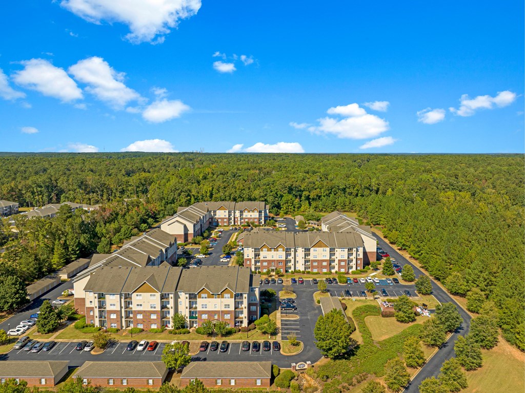 an aerial view of an apartment complex with trees and a blue sky
