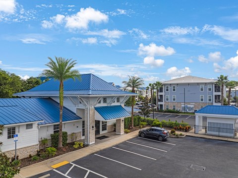 an empty parking lot in front of a building with a blue roof and palm tree