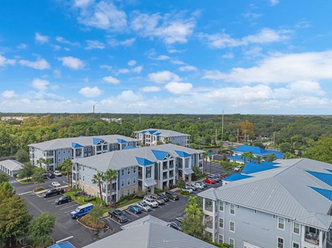 an aerial view of apartment buildings with parking lot and trees