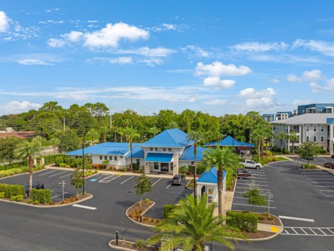 an aerial view of a parking lot with buildings and palm trees