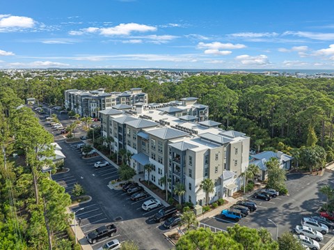 an aerial view of an apartment complex with trees and a parking lot