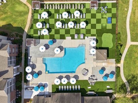 A large swimming pool surrounded by a grassy area and a checkerboard pattern.