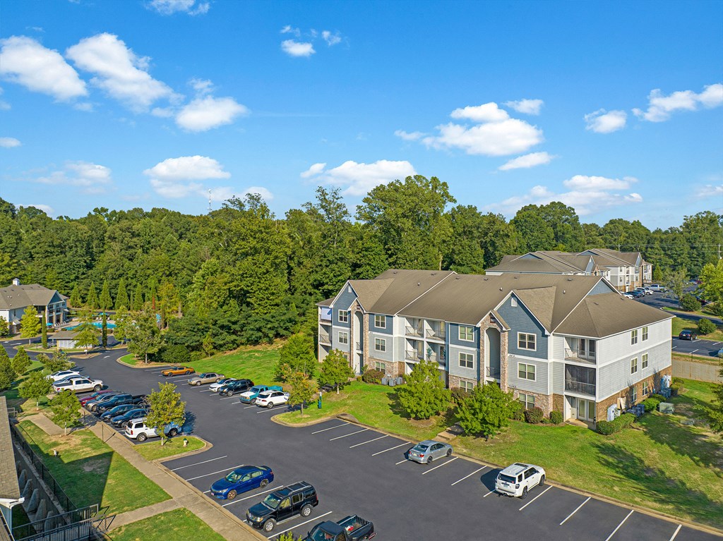 an aerial view of an apartment complex with parking lot and trees