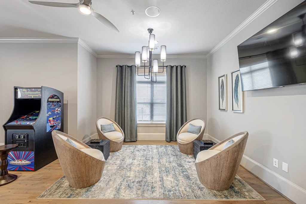 a living room with three chairs and a video game machine