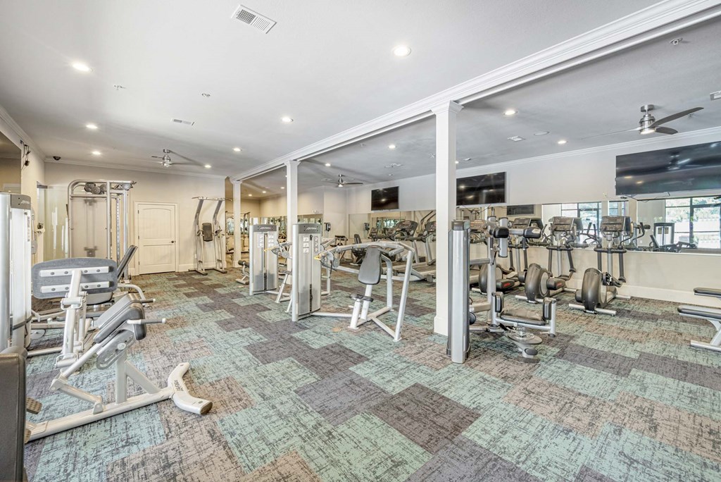 a gym with weights and cardio equipment in a room with glass doors