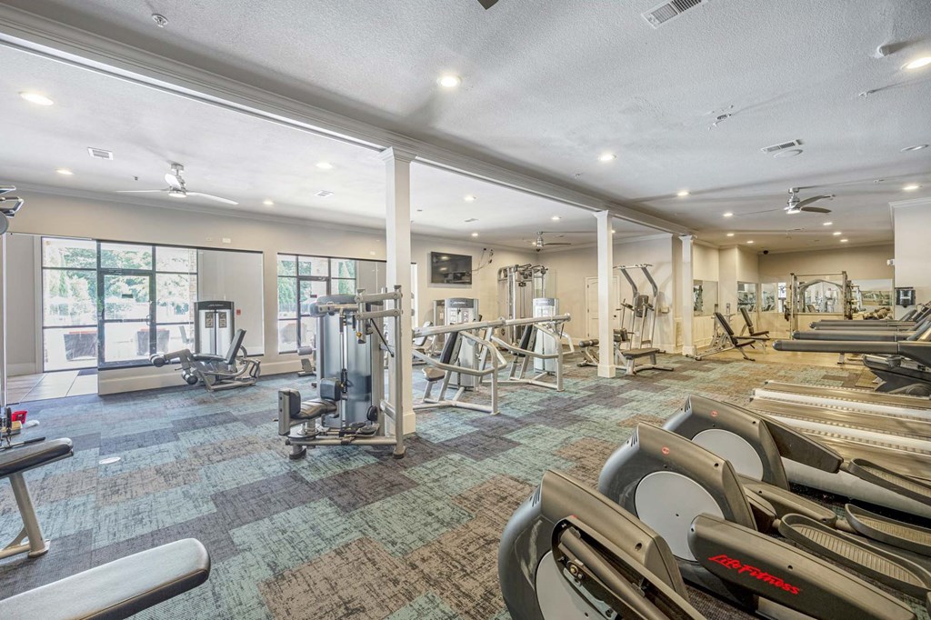a gym with weights and cardio equipment and windows