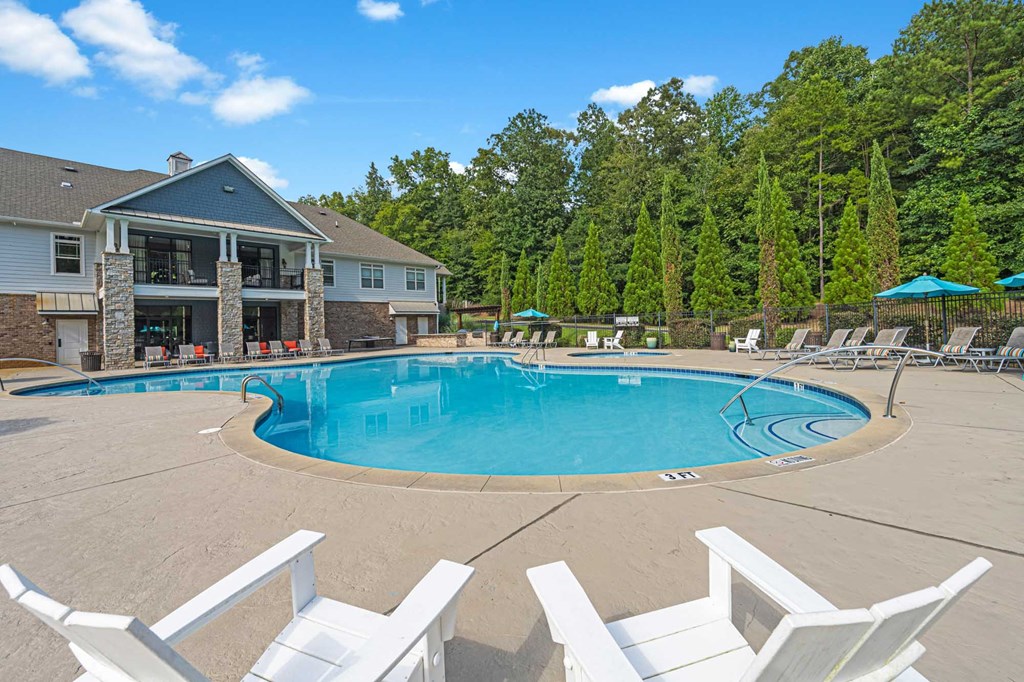 a swimming pool with chairs around it in front of a house