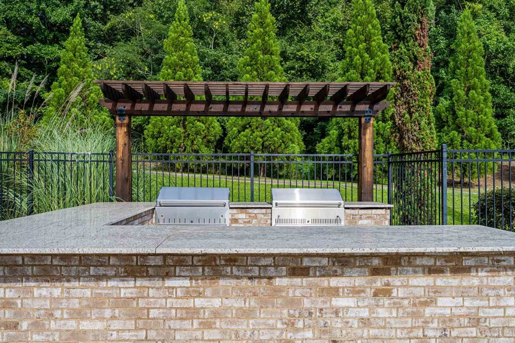 a brick patio with two stainless steel barbecue grills