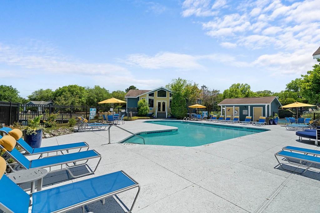 a swimming pool with lounge chairs and umbrellas around it