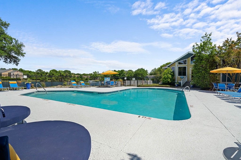 a swimming pool with chairs around it and a house in the background