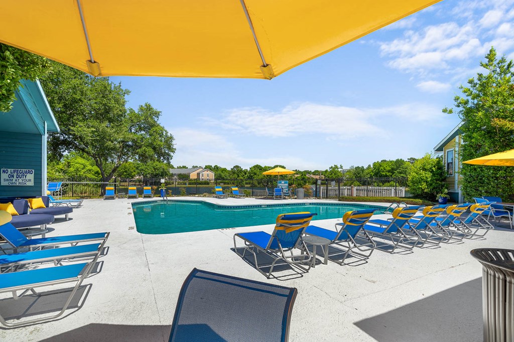 a pool with blue chairs and yellow umbrellas