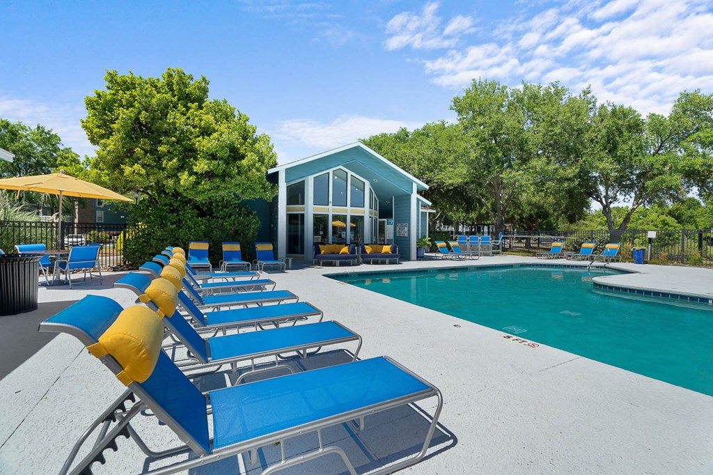 a pool with lounge chairs and a pool house in the background