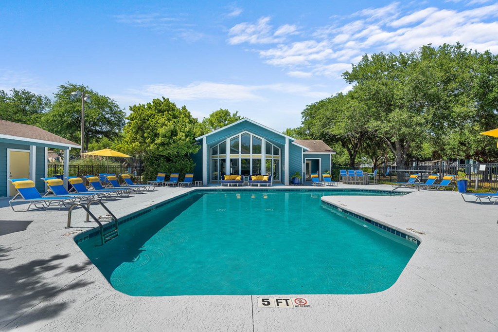 a swimming pool with blue chairs and a building in the background
