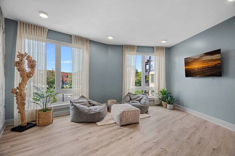 A living room with a large window, a wooden floor, and a painting on the wall.