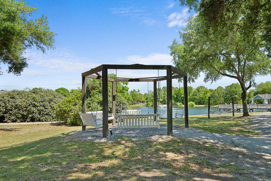 a park bench sitting under a canopy next to a lake