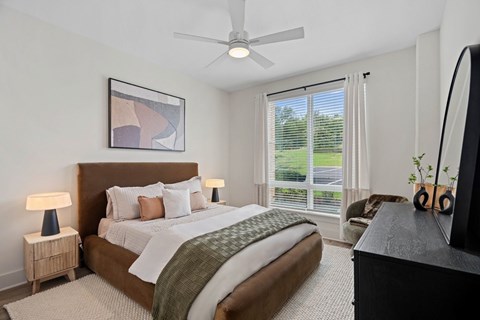 A bedroom with a large bed, a ceiling fan, and a painting on the wall.