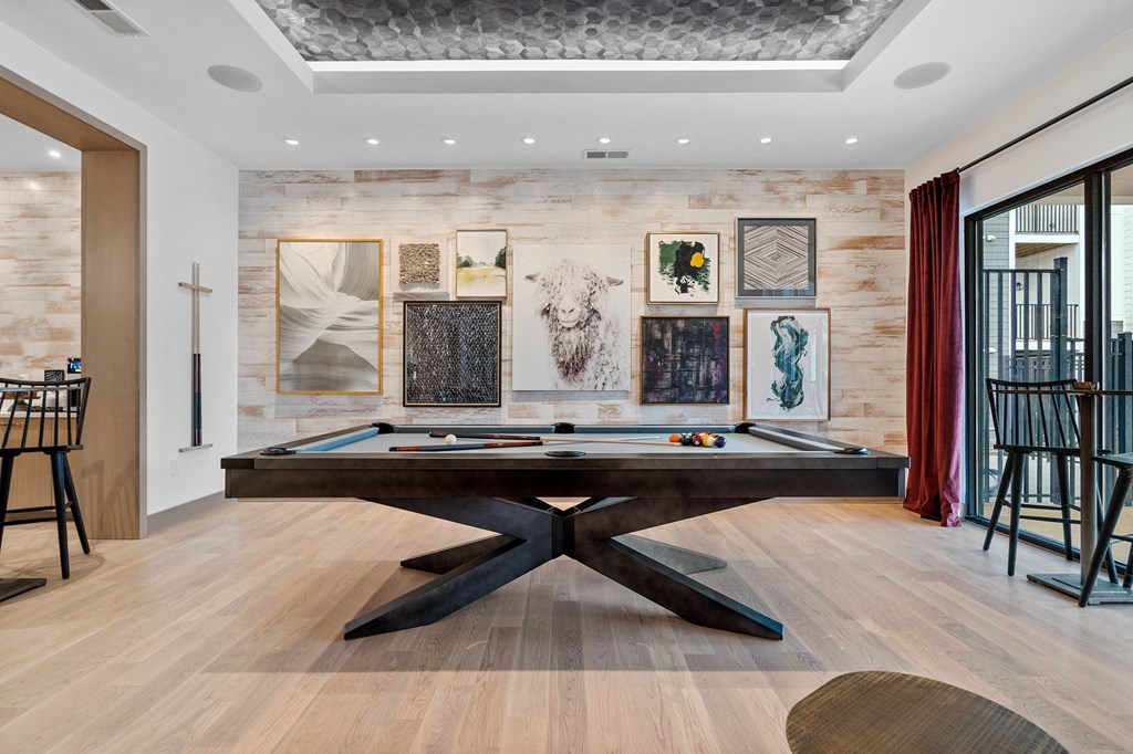 a game room with a pool table and paintings on the wall