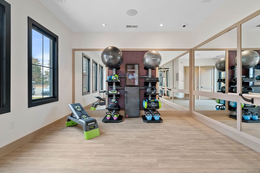 a home gym with weights and exercise equipment in a large room with windows