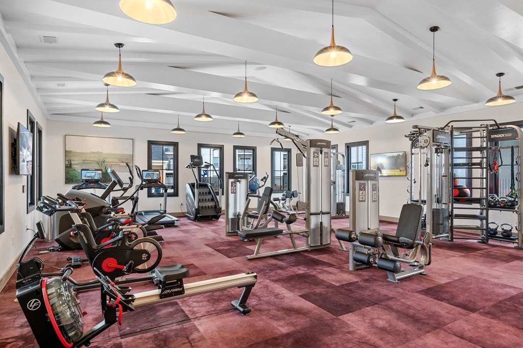 a gym with weights machines and lights on the ceiling