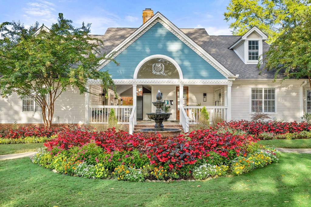 a house with a garden and a fountain in front of it