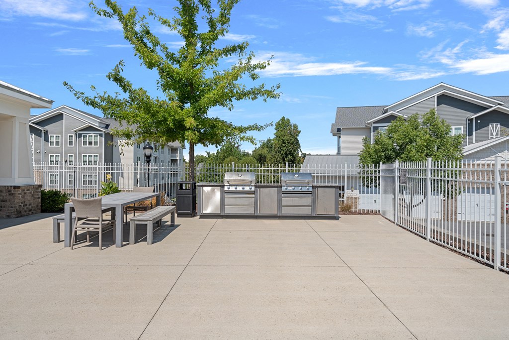a patio with a table and chairs in front of a fence