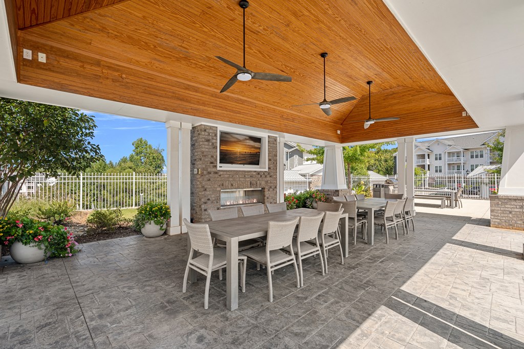 a covered patio with a table and chairs and a fireplace