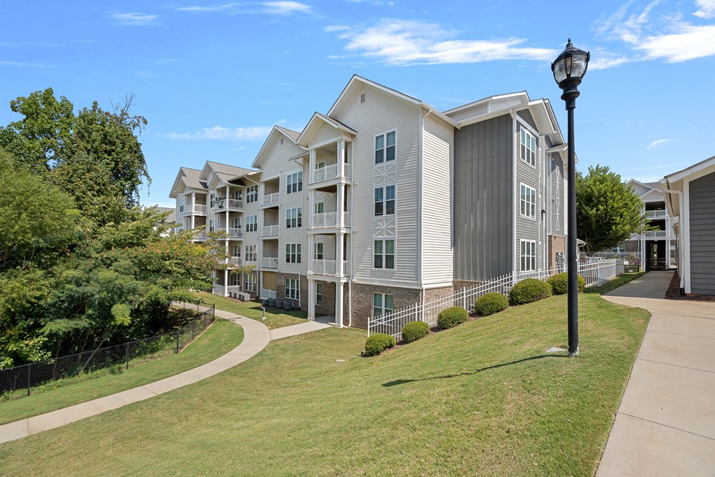 an apartment building on a sidewalk next to a grass field