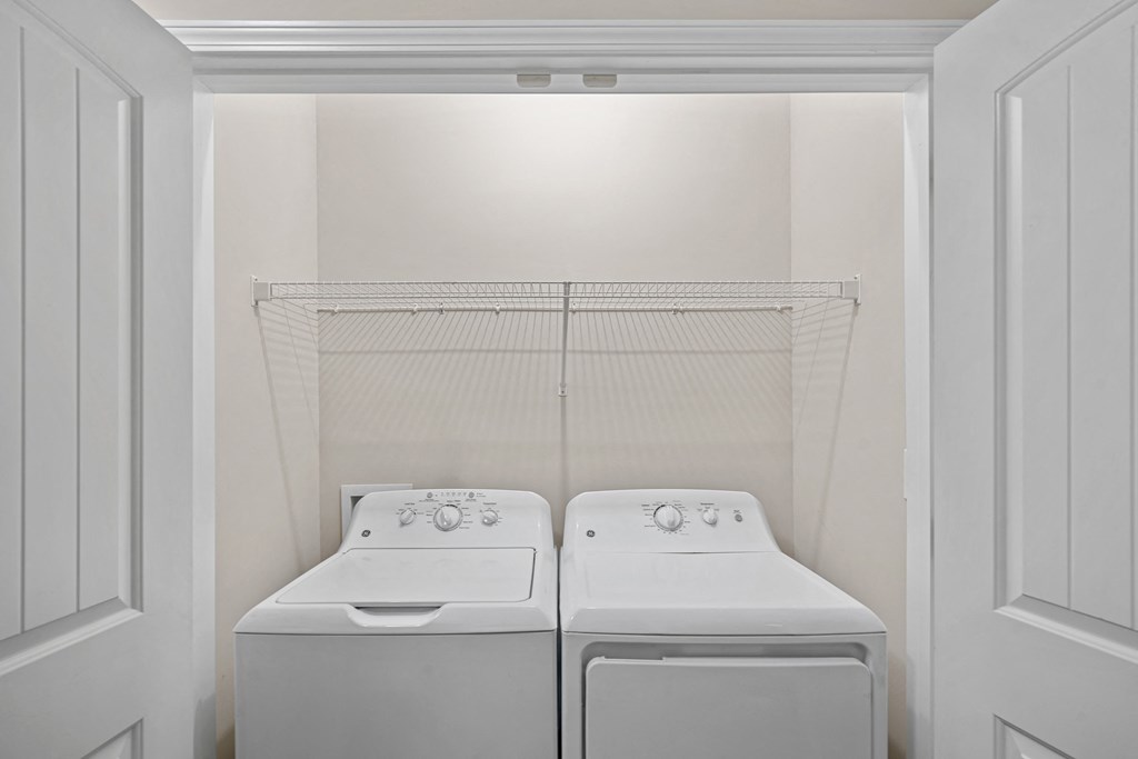 a white laundry room with two washes and a dryer