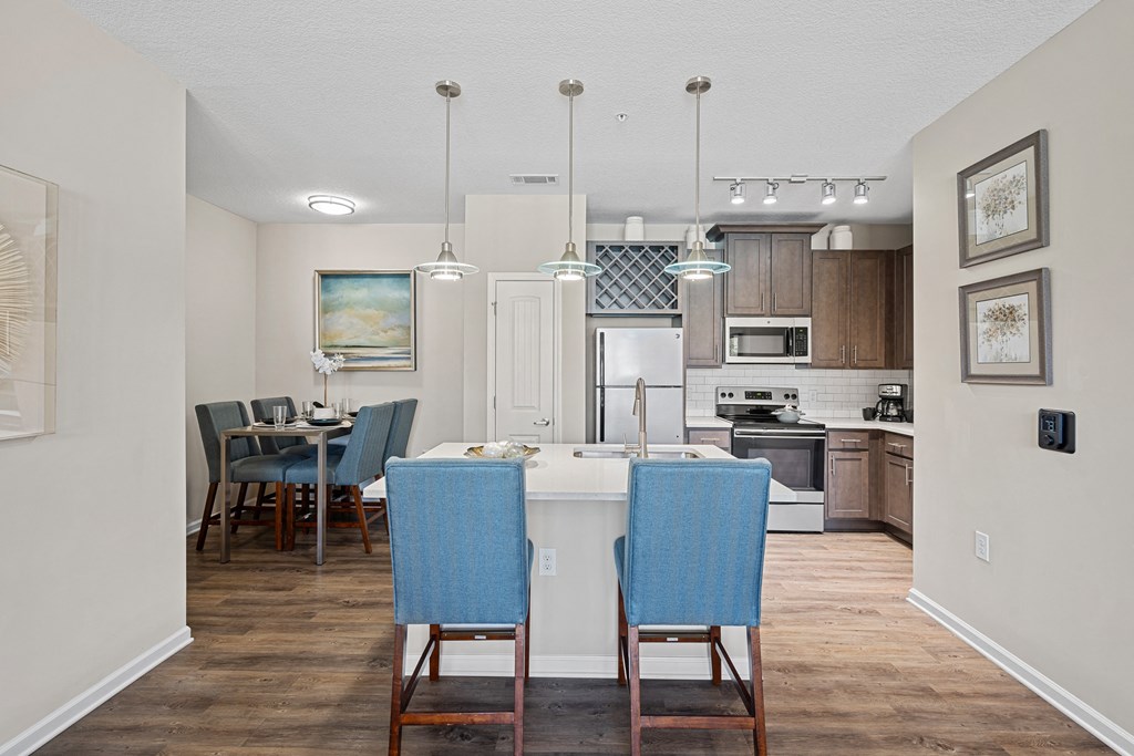 an open kitchen and dining area with blue chairs and a white counter top