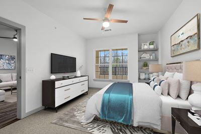 Spacious bedroom with a lighted ceiling fan and large window at 8 West in Greensboro, NC