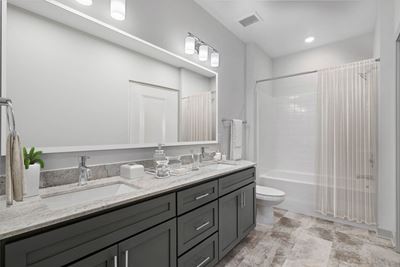 Spacious bathroom with dual vanities, designer lighting, and relaxing tub at 8 West in Greensboro, NC
