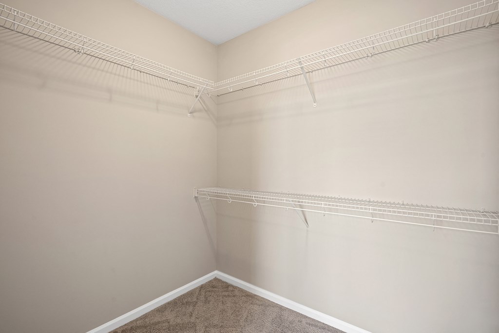 an empty closet in a home with white walls and carpet