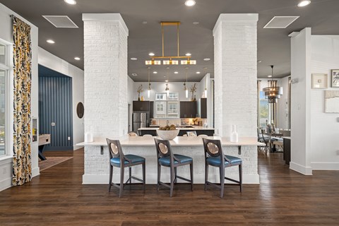 a large kitchen with a white island and blue chairs