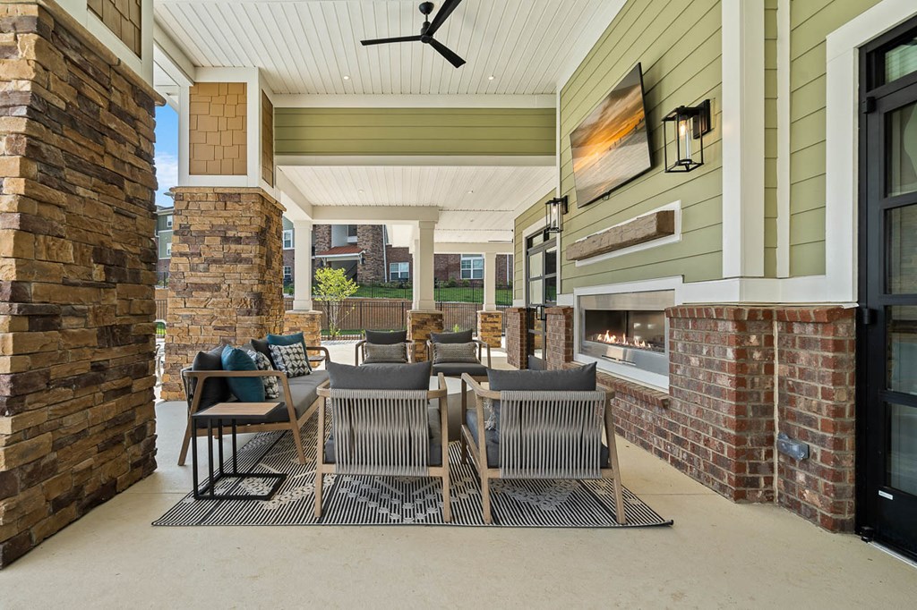 a covered patio with a table and chairs and a fireplace