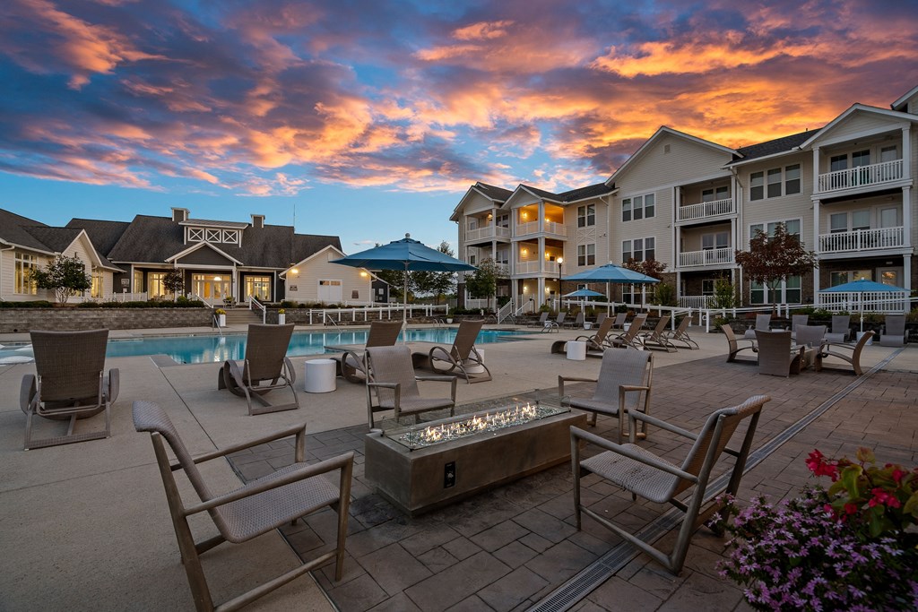 a swimming pool with chairs and umbrellas at dusk