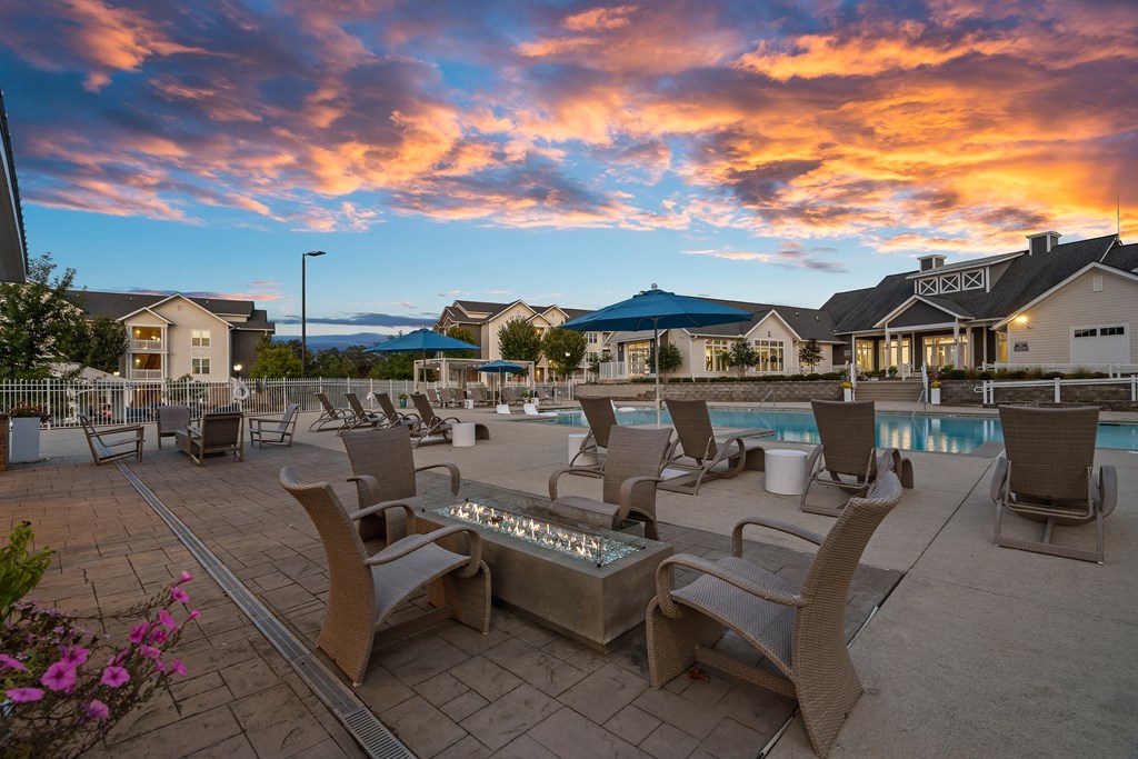 a swimming pool with chairs and tables at dusk