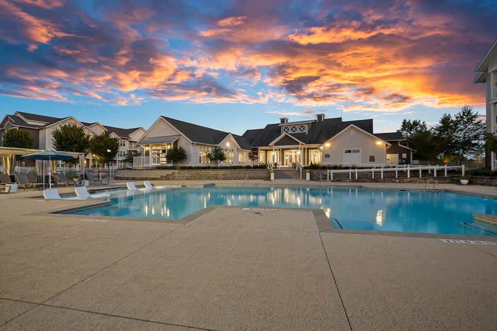 a swimming pool at sunset with houses in the background