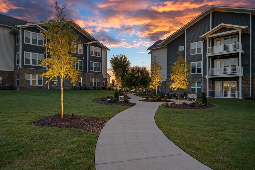 a sidewalk leading to an apartment building at sunset