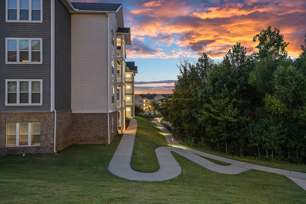 a winding sidewalk between two buildings with a sunset in the background