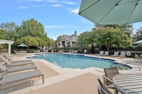 a swimming pool with chairs and a house in the background