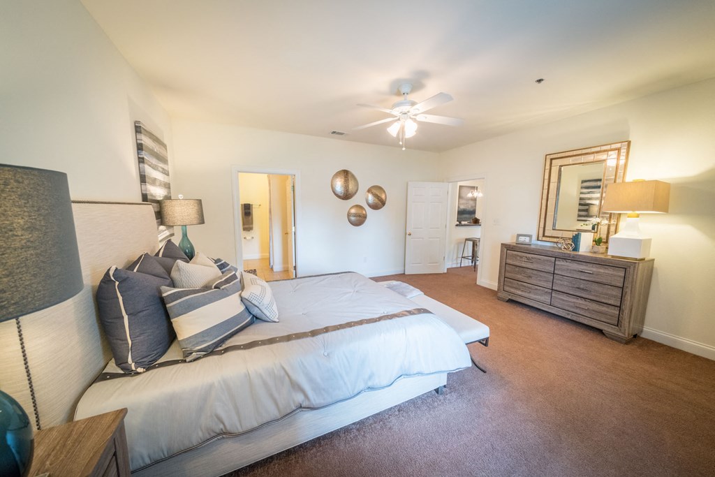 a bedroom with a bed and a dresser and a ceiling fan