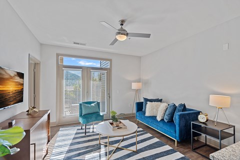 A living room with a blue couch and a ceiling fan.